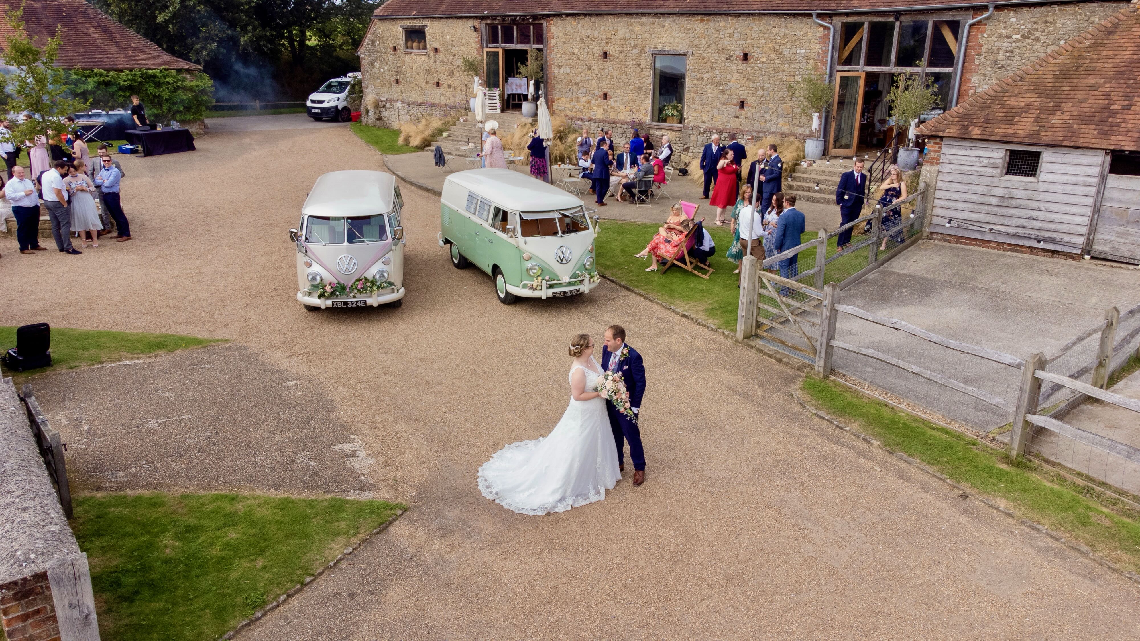 Aerial view of a wedding reception at a barn venue, with the couple in the foreground